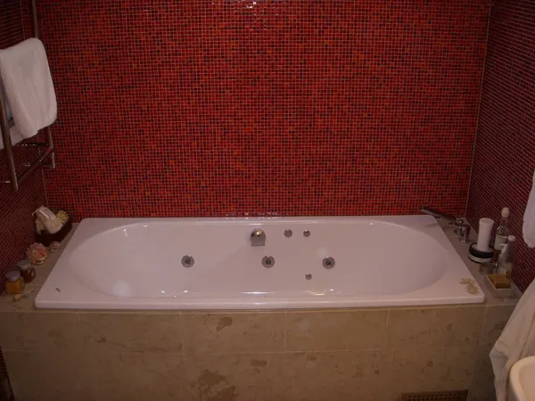 Badrum med röd mosaik och bubbelbadkar