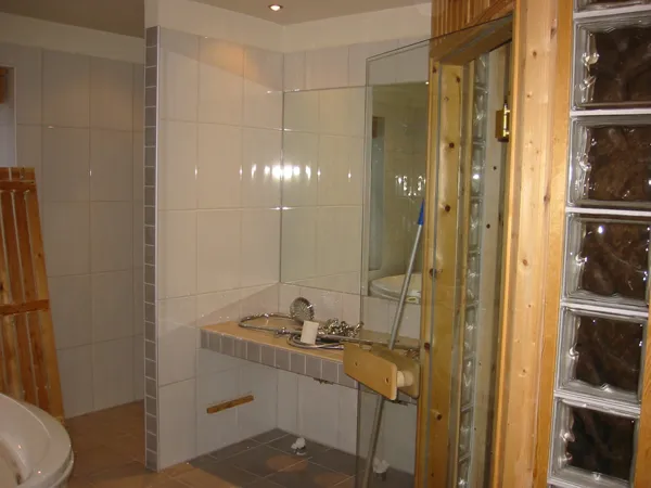 Badrum med glasblock, hörnbadkar och mosaikbård
